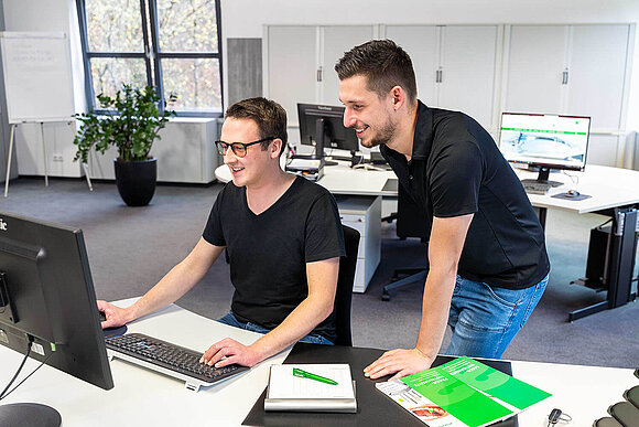 Kollege wird von einem anderen Kollegen bei der arbeiten am Computer unterstützt.